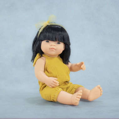 Miniland lėlė mergaitė geltonu romperiu (azijietė, 38 cm) mėlyname fone