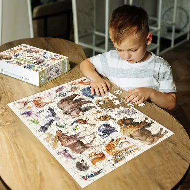 Berniukas dėlioja montessori tipo dėlionę vaikams apie miško gyvūnus
