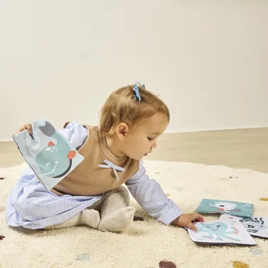 Mergaitė dėlioja minkštas kontrastingas korteles kūdikiams nuo 0 mėn.