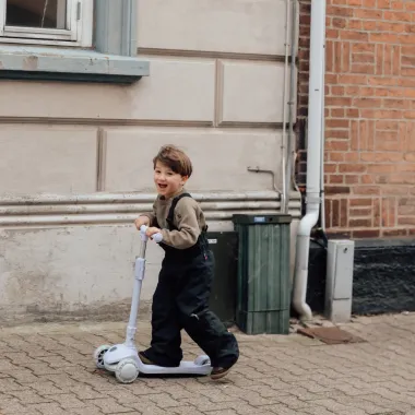 Vaikas važiuoja violetiniu vaikišku paspirtuku su 3 šviečiančiais ratais