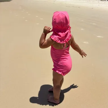 Mergaitė eina paplūdimyje su Vanilla Copenhagen maudymosi kepuryte