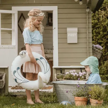 Berniukas dėvi maudymosi žalsvą kepurę su snapeliu ir žaidžia su mergaite