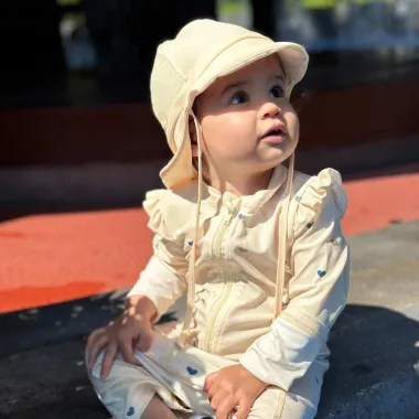 Mergaitė sėdi prie baseino su šviesia maudymosi kepure