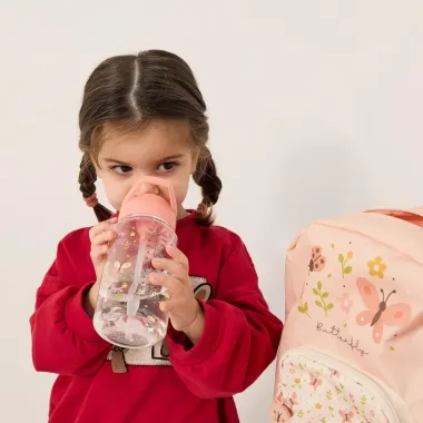 Mergaitė geria iš Miniland Kiddie Bottle Butterfly gertuvės su šiaudeliu