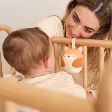 Mama žiūri į kūdikį lovytėje, šalia kabo migdukas su baltuoju triukšmu Miniland Fox Dreamer